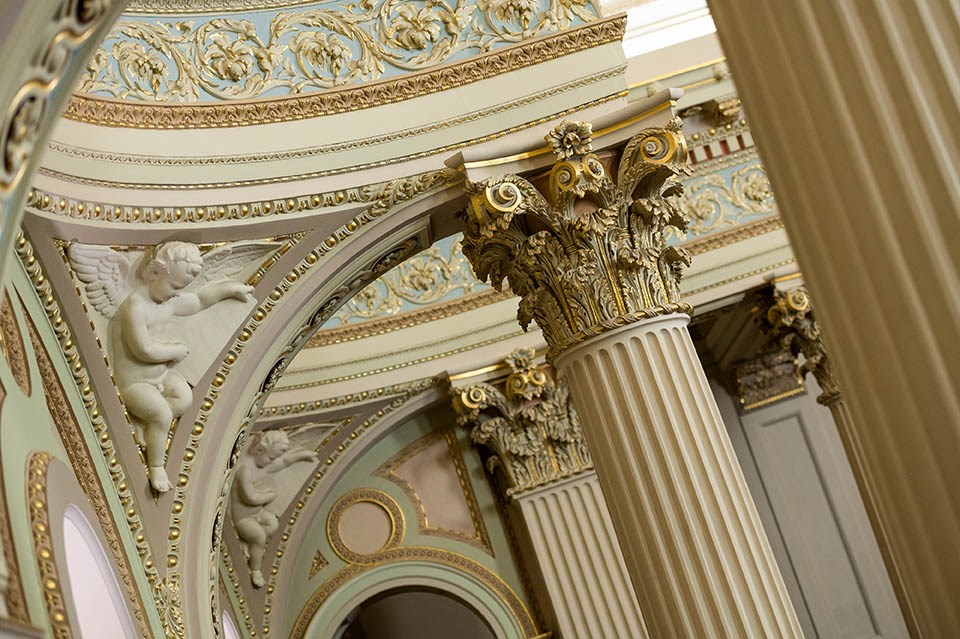 A detail of the internal columns of Parliament House with sculptures of cherubs and agapanthus
