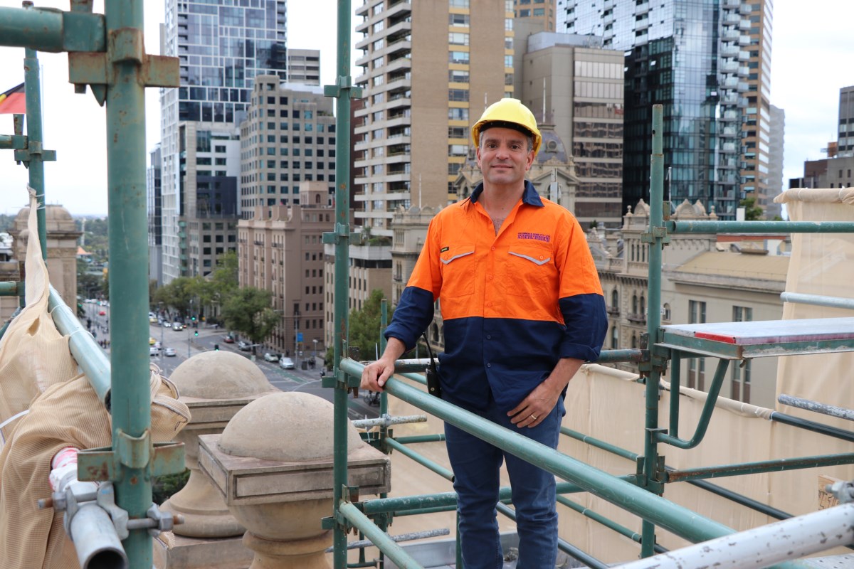 Joe Michienzi, stonemason, poses on scaffolding at the restoration worksite, overlooking the city.